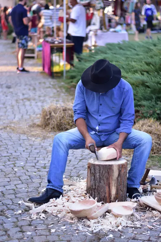 Lingurar rom cu pălărie, cioplind un castron pe un buștean, la Balkanik Festival