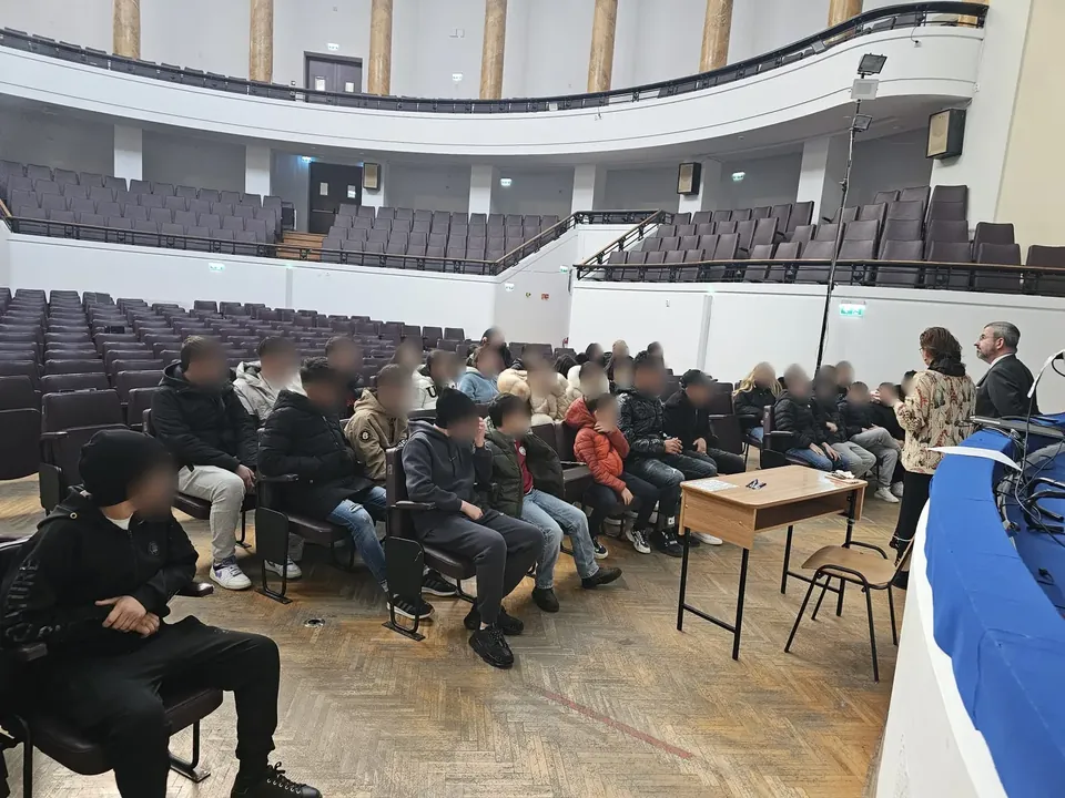 Elevi din Cernica așezați în Aula Facultății de Drept, ascultând doi profesori